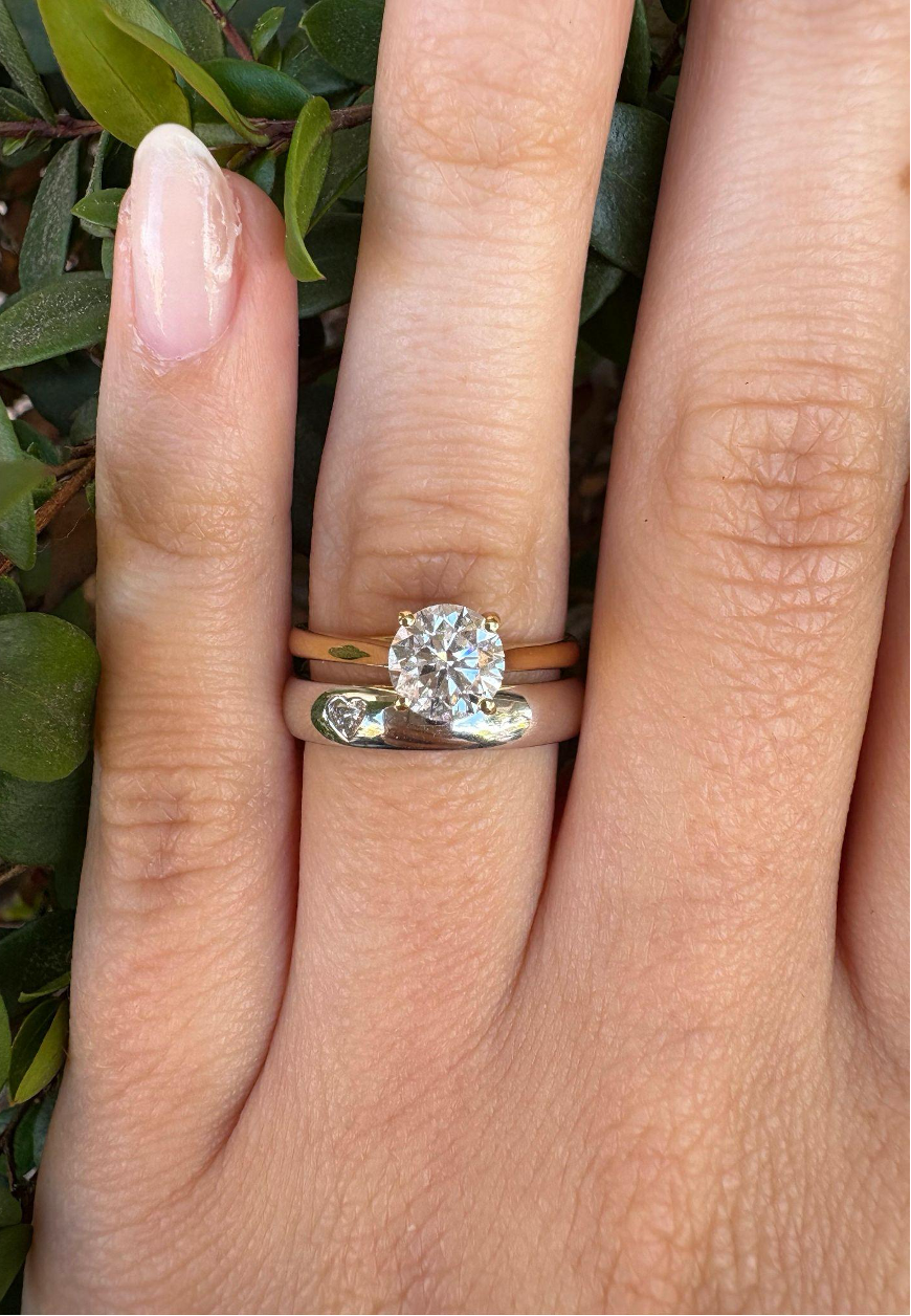 Rigel Solitaire Engagement Ring with 1.00 Ct Round Lab Grown Diamond in 18Kt yellow gold and Venus Wedding Band with 1 Heart-Shaped Lab Grown Diamond in 18Kt white gold