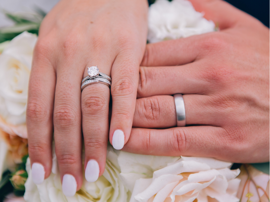 Groom with white gold wedding band holding hands with bride wearing solitaire engagement ring